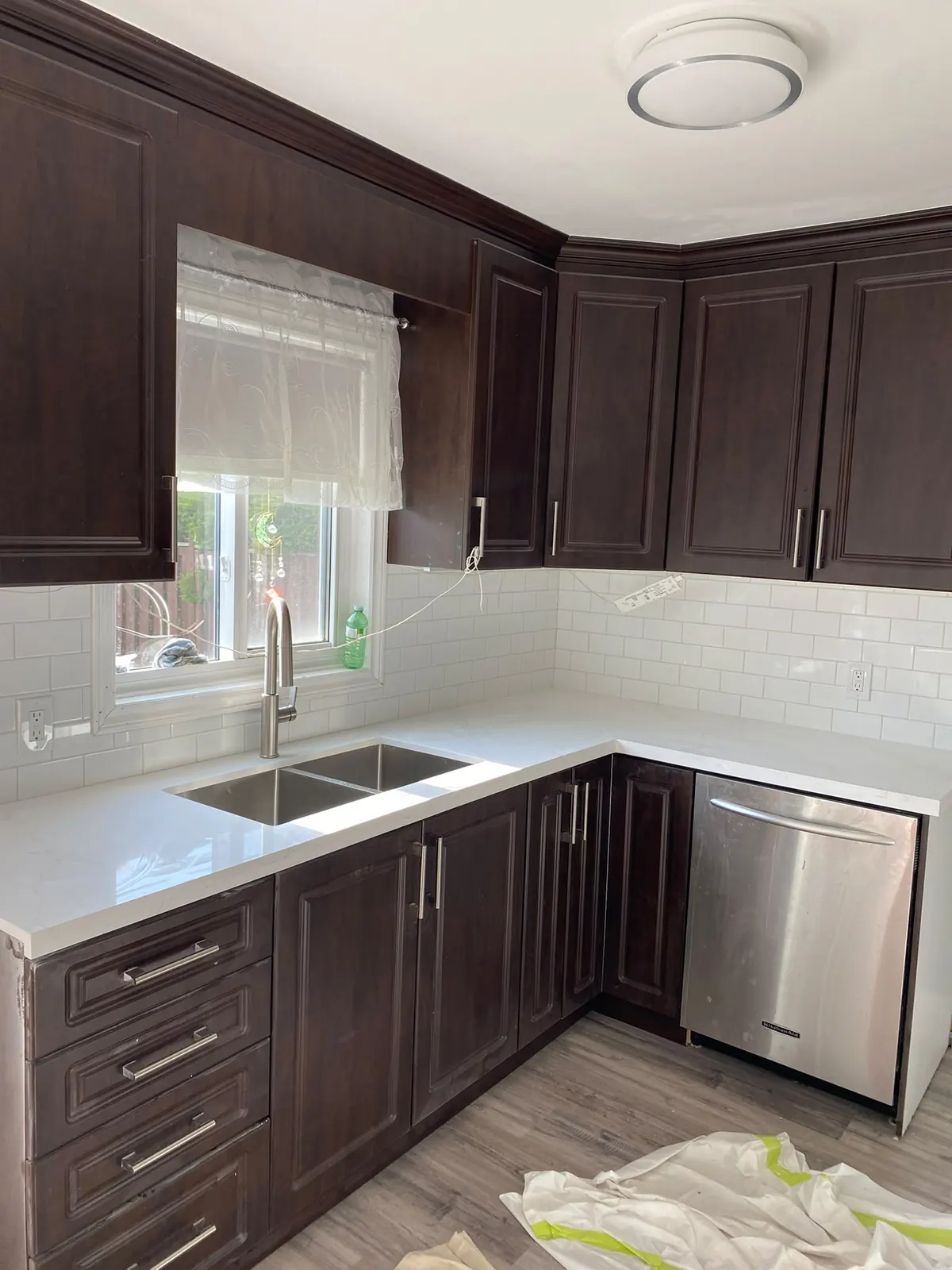 After: the same dark cabinets with white counters, white subway tile backsplash and new plank flooring